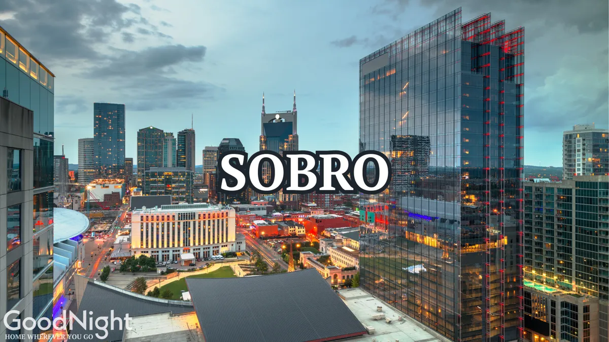 A panoramic city skyline at dusk with SOBRO signage illuminated, highlighting Nashville’s modern and energetic vibe. The glowing city lights and visible urban activity evoke the excitement of exploring downtown neighborhoods after dark.
